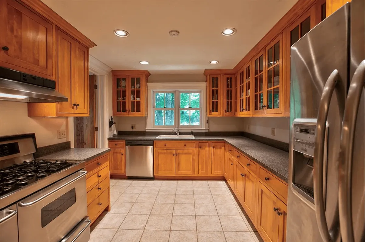 A beautifully appointed kitchen with stainless steel appliances, wooden cabinetry, and a sink overlooking a window. The space is bathed in natural light, highlighting its functionality and warmth, perfect for cooking, baking, or entertaining guests.