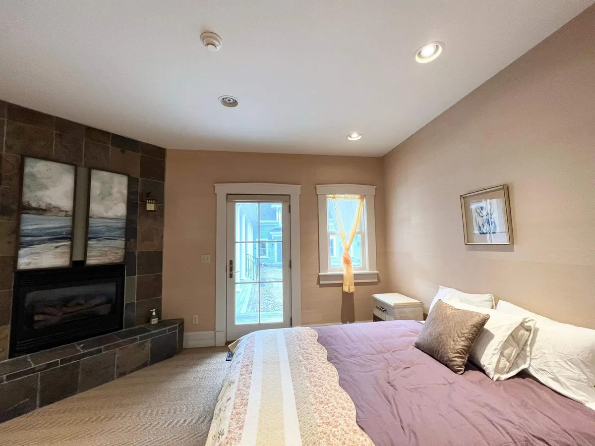 A tranquil suite with a bed, a fireplace for cozy evenings, sliding doors opening to natural light, and elegant artwork. The design blends comfort and a touch of luxury, perfect for unwinding after a day with loved ones.