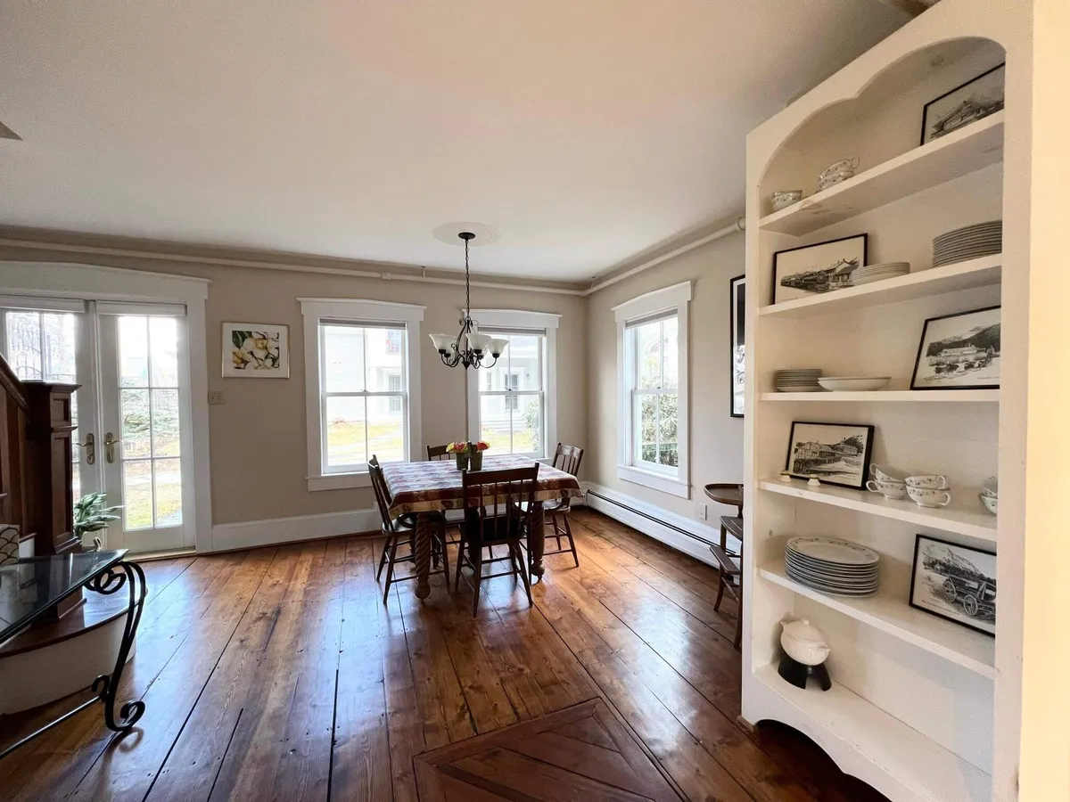 A cozy dining area centered around a large wooden table beneath a glowing chandelier, with a built-in shelf providing character and warmth. The arrangement is ideal for family meals, holiday dinners, or group celebrations.